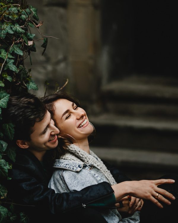 Young couple hugging sit near greenery wall and laughing
